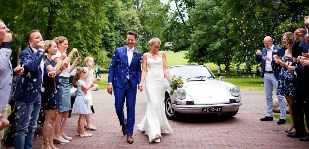 bruidspaar komt uit de auto voor stadsvilla sonsbeek, loopt hand in hand