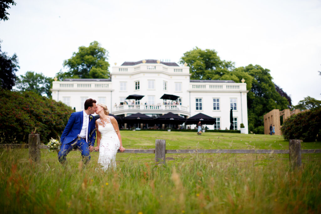 Stadsvilla Sonsbeek Trouwen Buiten, bruidspaar kust elkaar voor de witte villa van buitenplaats sonsbeek